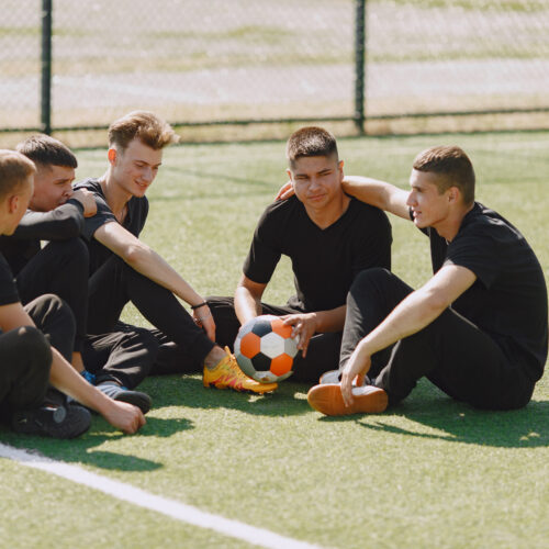 Men play socer at the park. Tournament on mini-footbal. Guy in a black sportsuits.